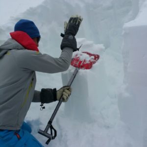 Bergführer untersucht schneedecke mitCompression test