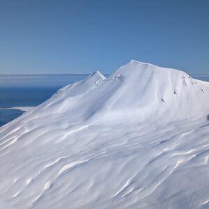 Verschneiter Gipfel mit Blick aufs Meer in Nordisland