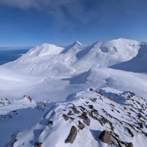 Gipfelblick über verschneite Berge und Meer in Nordisland