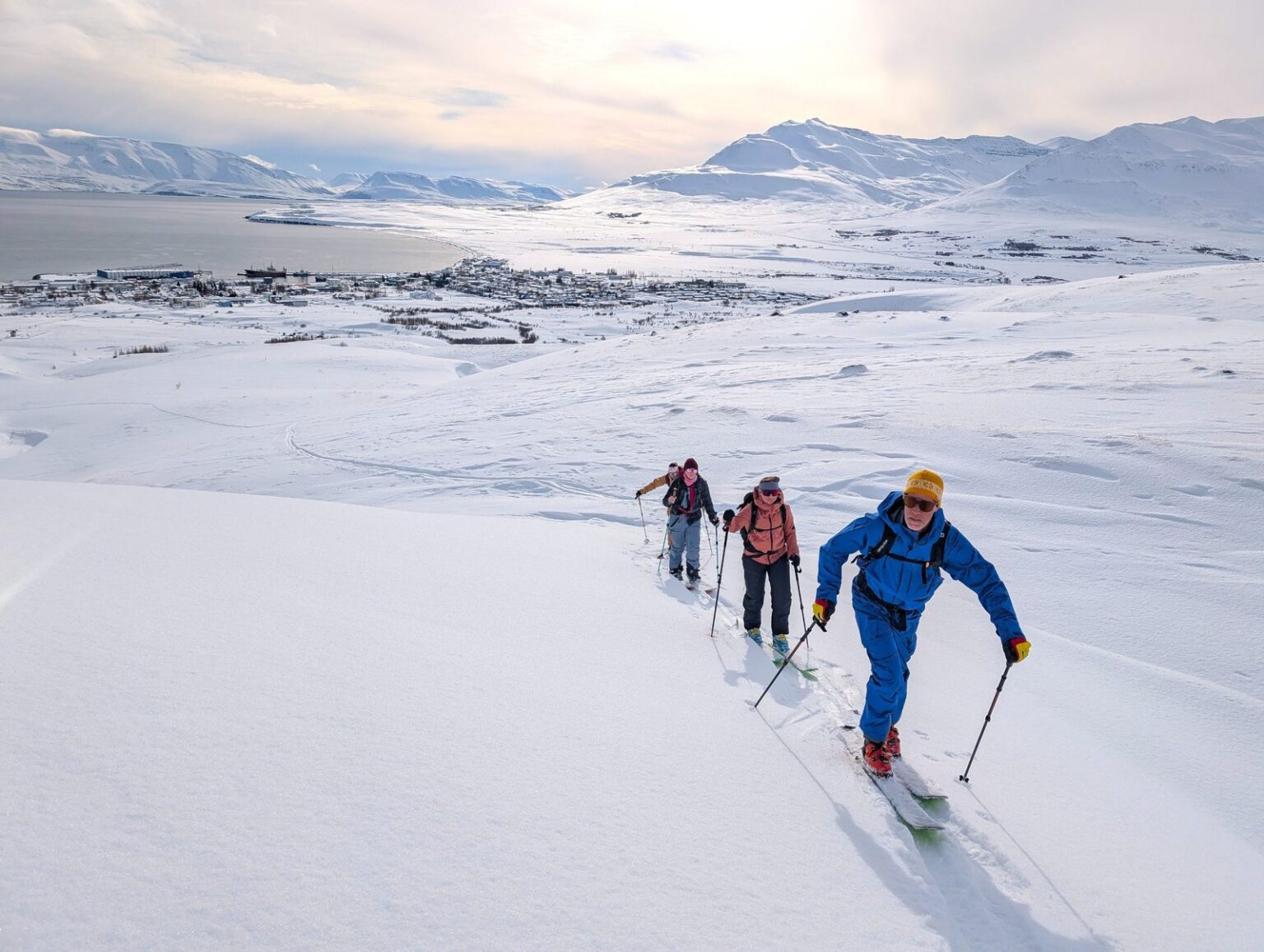 Skitourengruppe im Aufstieg unter grauem Himmel über dem Fjord