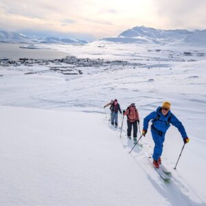 Skitourengruppe im Aufstieg unter grauem Himmel über dem Fjord